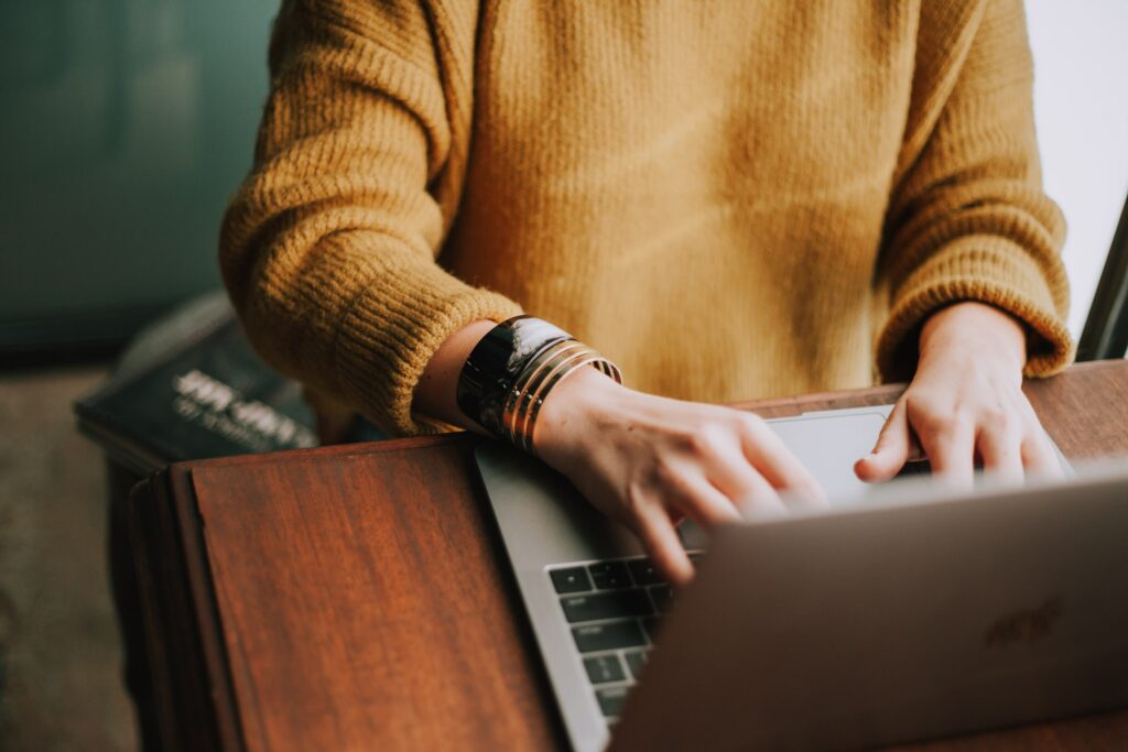 A cropped image showing a person at a desk using a laptop